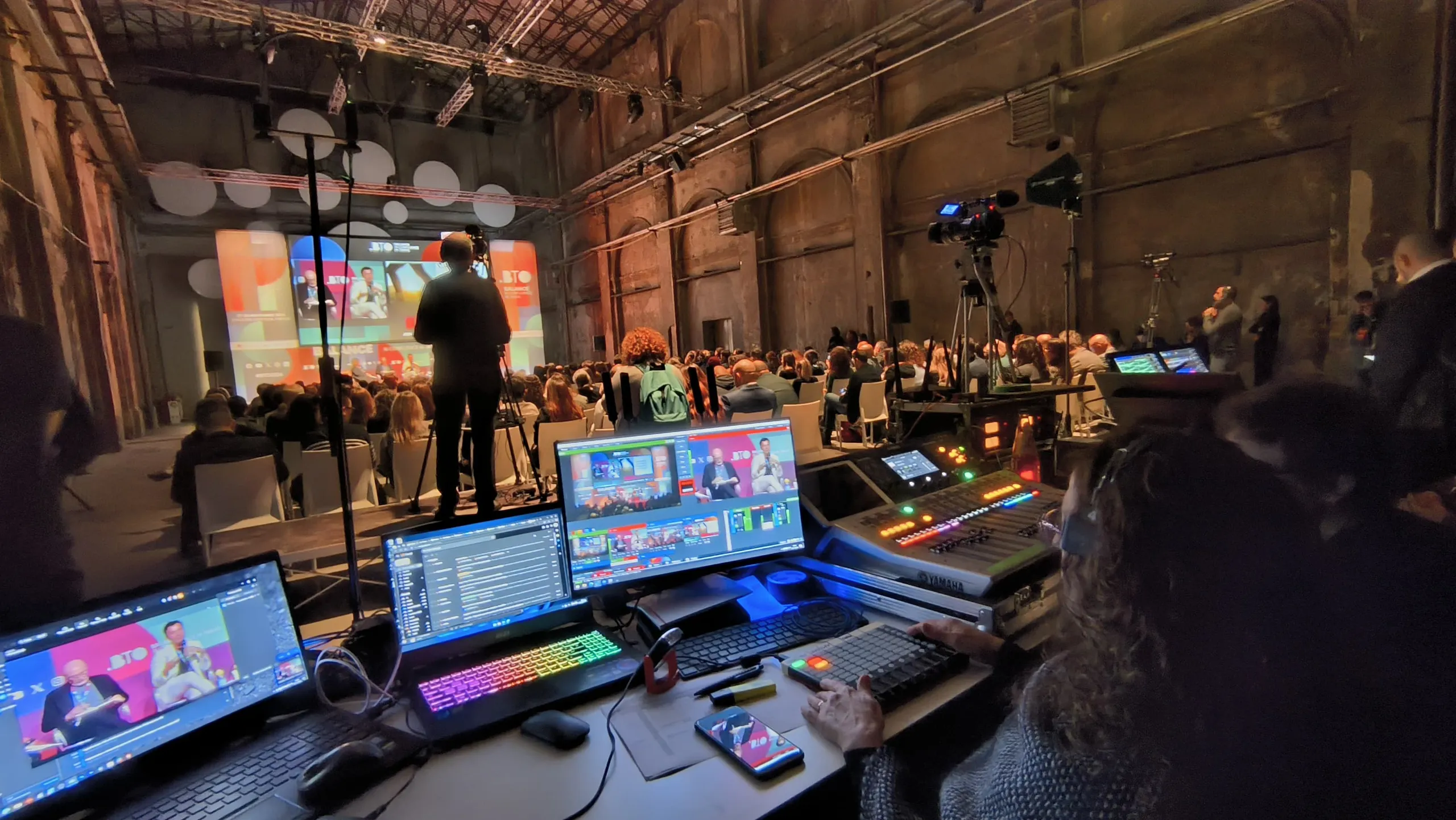 Regista che segue un convegno davanti al mixer video per la gestione di pi&ugrave; camere e contributi
